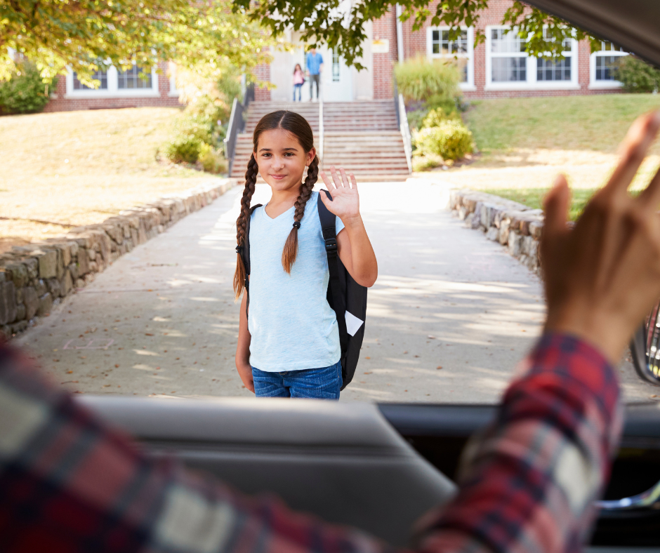 girl waving goodbye to parent in their car