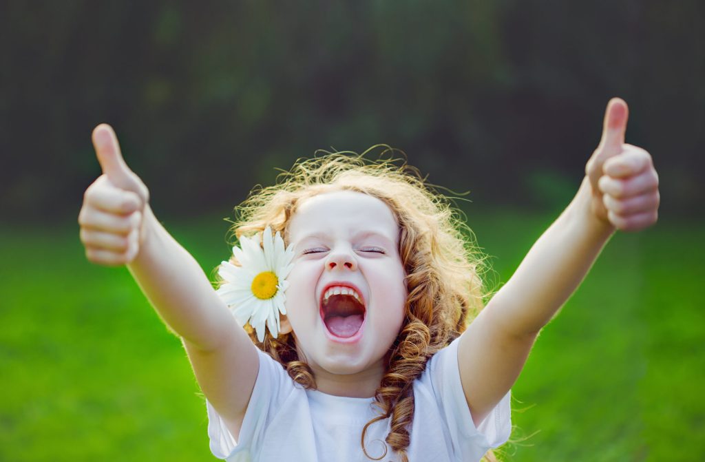 Laughing girl showing thumbs up.