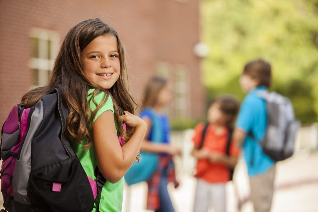 Back to School: Elementary-age children, girl on school campus.